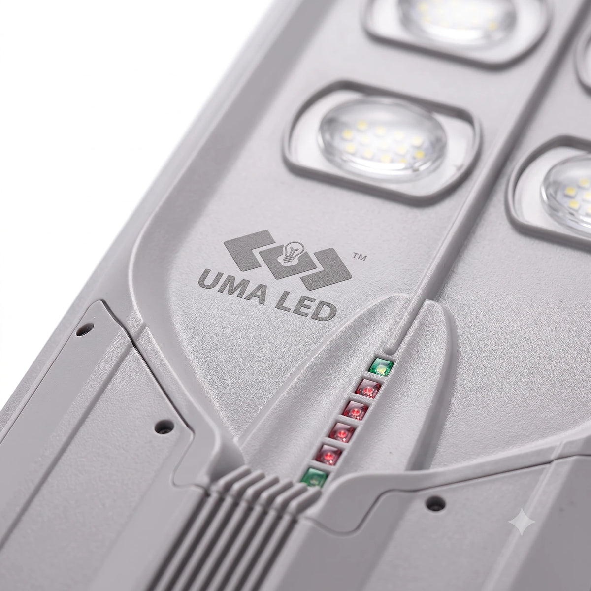 Close-up of a gray UMA LED solar light fixture showing the brand logo, textured plastic housing, and small indicator lights.