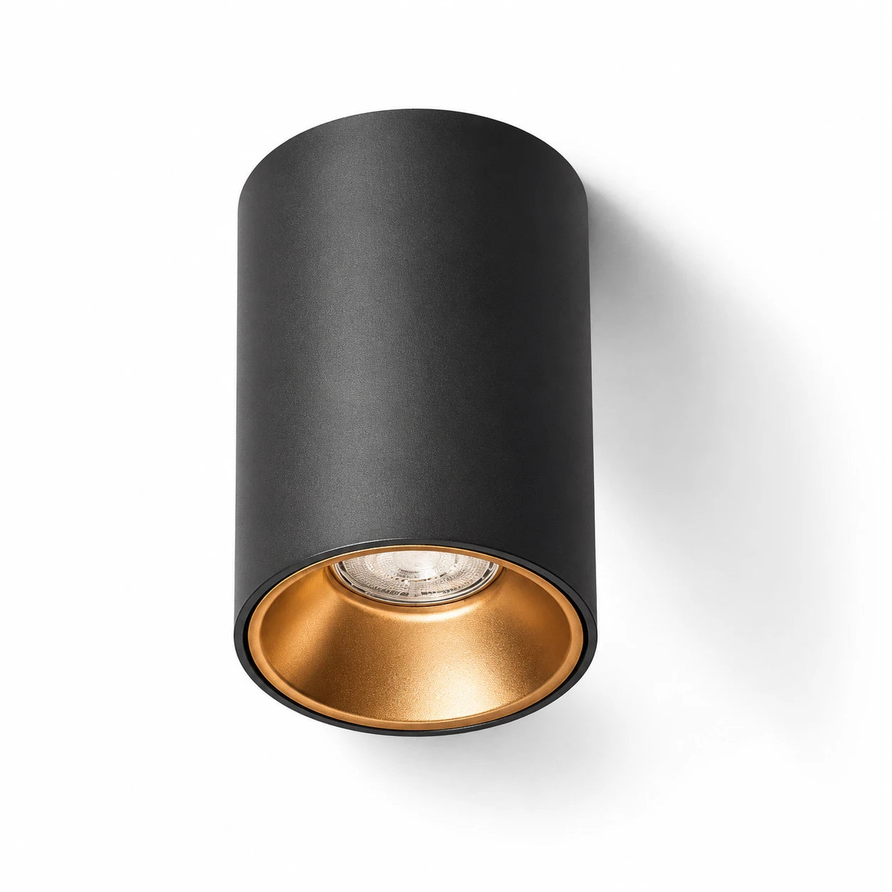 Cylindrical ceiling light fixture with black outer shell and gold inner core on a white background
