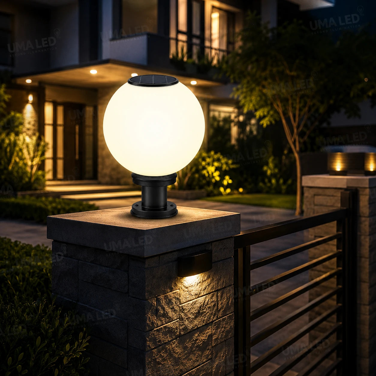 Solar outdoor bollard light with a glowing spherical globe on a stone pillar at night in front of a modern house.