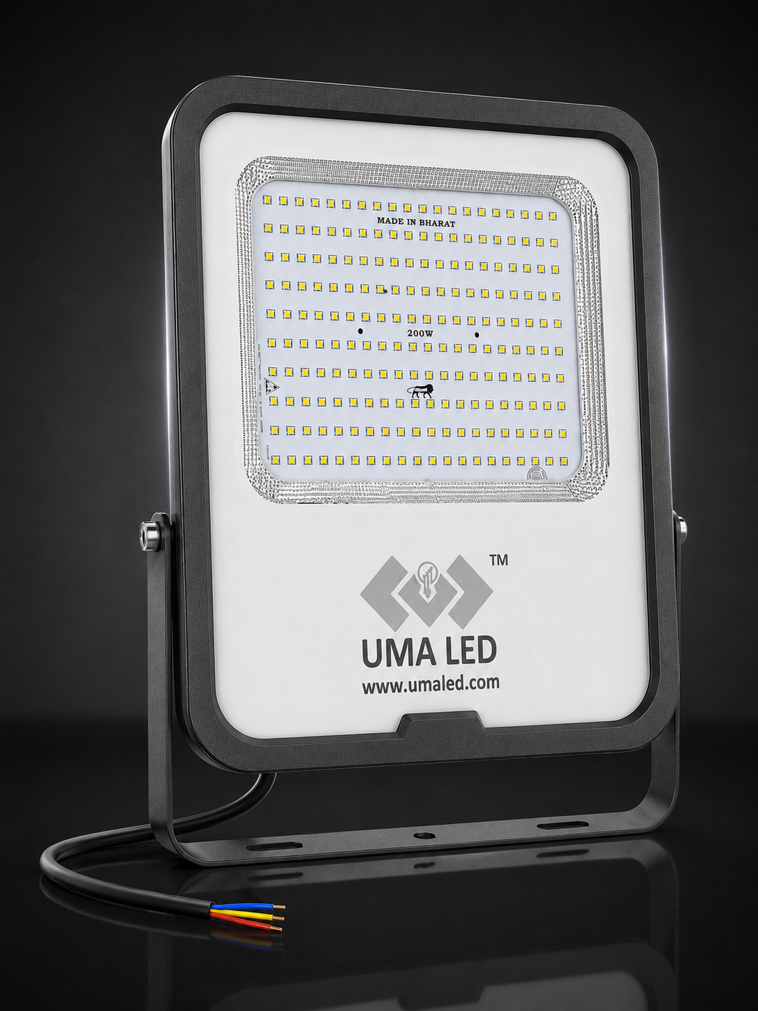 UMA LED square floodlight with a white faceplate, black housing, and visible internal LED array, shown on a dark reflective studio background with a cable and small multicolored wire visible at the bottom.