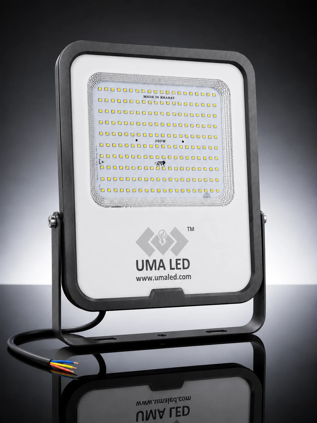 UMA LED 300W square floodlight with a white faceplate, black metal housing and bracket, and a black cable with multicolored wire ends, shown on a reflective black background.