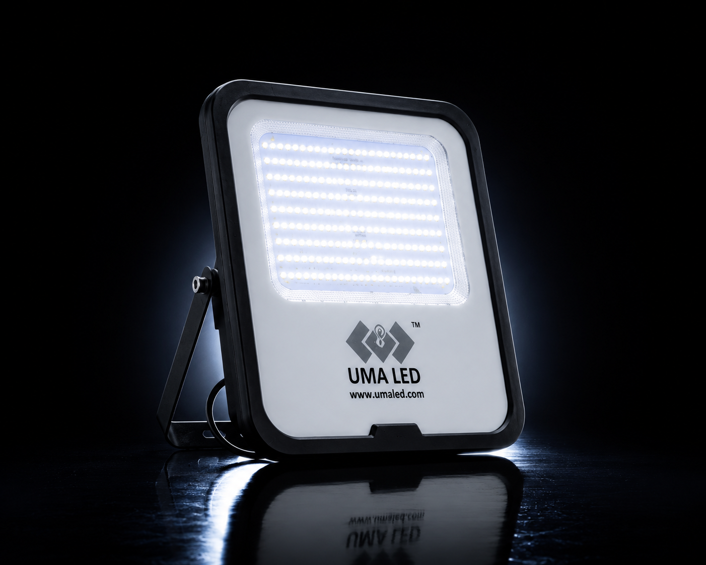 UMA LED square floodlight with a black frame and white LED panel, shown illuminated on a reflective black surface against a dark background.