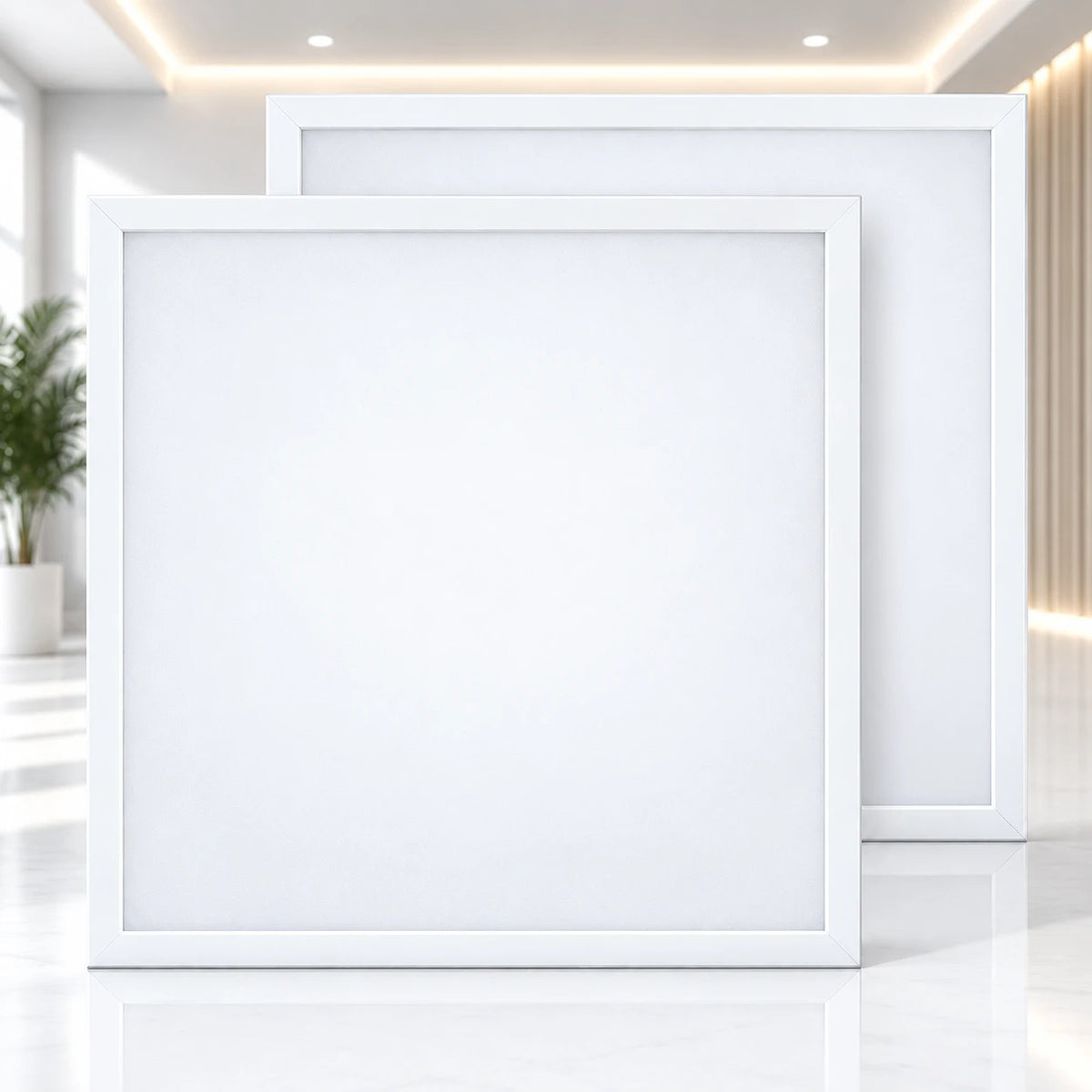 Two square white LED panel lights with slim white frames, displayed in a clean, modern interior setting with warm ceiling lights and a blurred plant in the background.