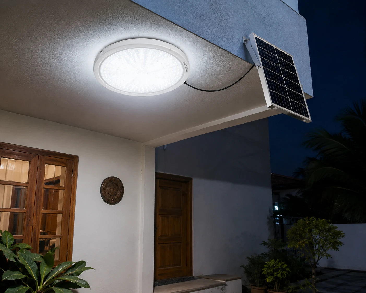 A solar-powered LED ceiling light installed on the underside of a house roof, with a small solar panel mounted on the exterior wall at night.