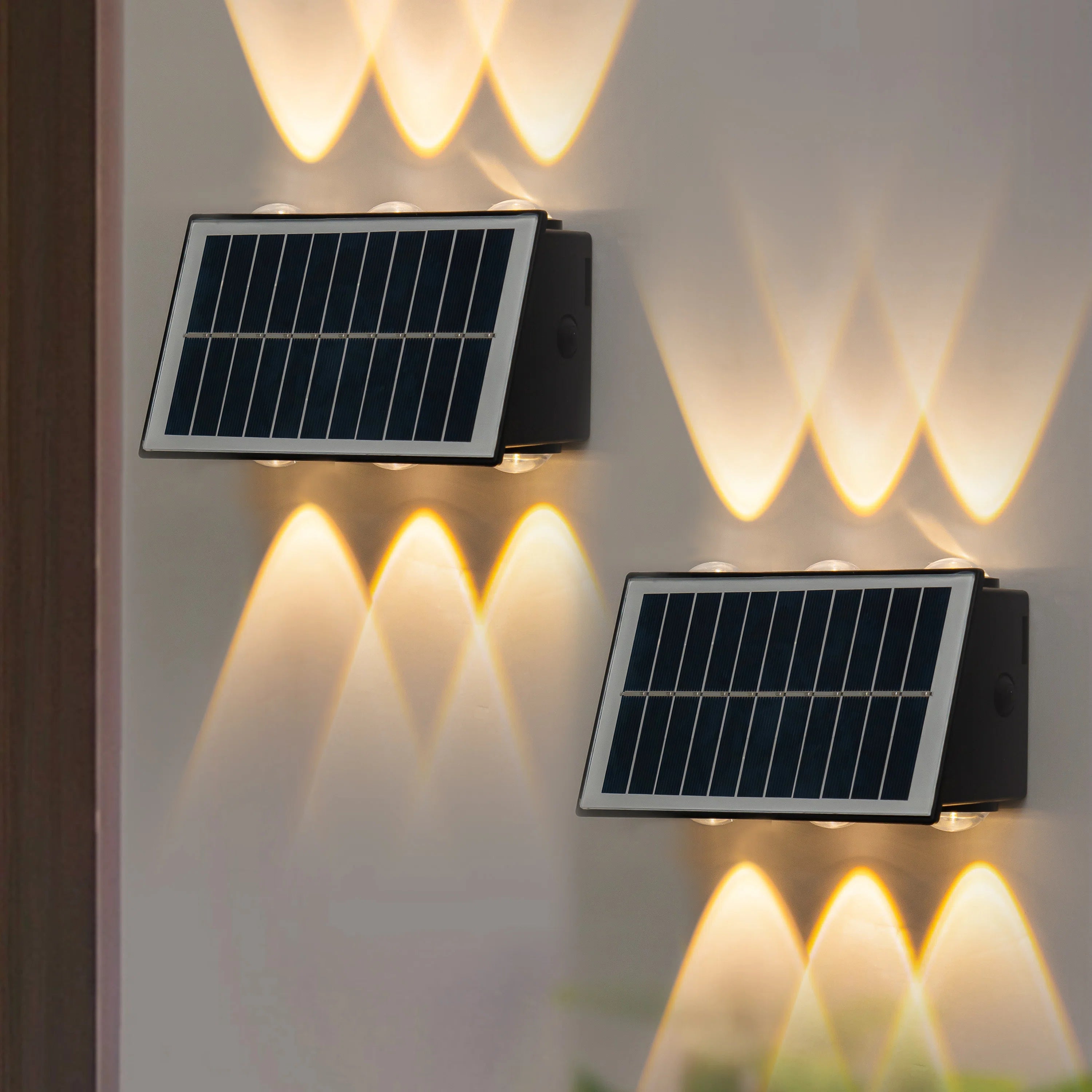 Two solar-powered wall lights on a wall with warm glow