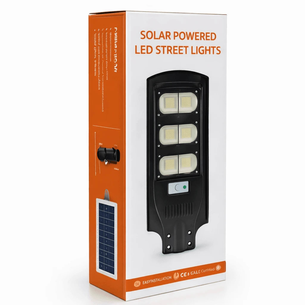 A boxed solar-powered LED street light product package on a light gray studio background. The box is mostly white with orange side panels and shows a large black street light graphic with four illuminated lens areas and a small solar panel illustration on the front.